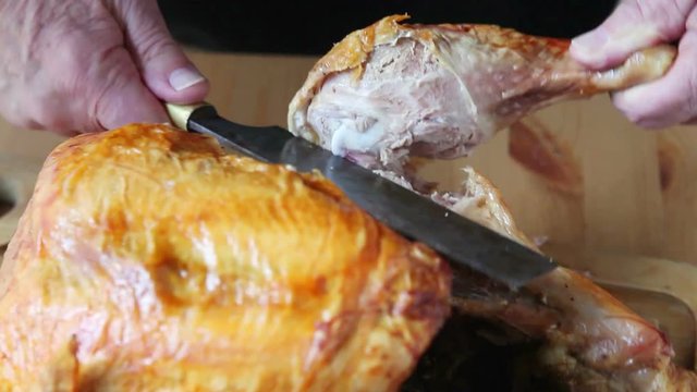 A man cuts a Thanksgiving turkey leg