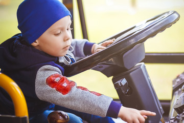 Little boy driving a big bus getting ready to start a car