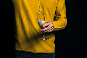 Young man on party pours champagne in glass