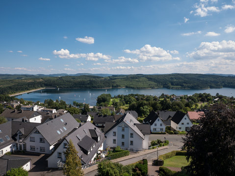 Panoramic view over the lake Sorpesee with some sailing boats and sone houses of Langscheid in Sauerland, Germany in the front