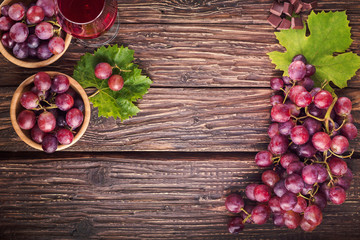 Grapes bunch with leaves and glass of wine  on a old wooden background. Top view with copy space - 237028676