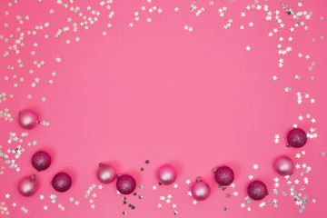 Pink Christmas background with Christmas ornaments and silver confetti. Copy space, top view