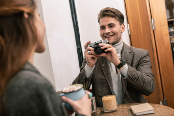 Man photographing woman while sitting in a cafe