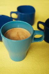 Coffee in a blue cup on a yellow background