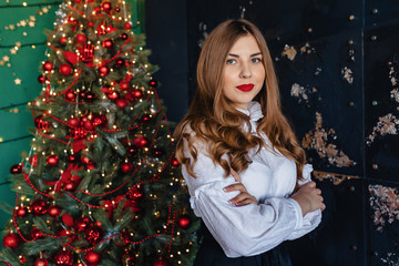 young attractive girl in festive clothing on the background of a Christmas tree, new year concept