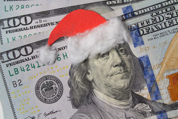 Benjamin Franklin in a Santa Claus hat on a bill. Christmas decorations © DmyTo