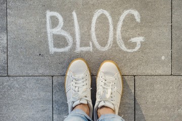 View from above, female feet with text blog written on grey sidewalk
