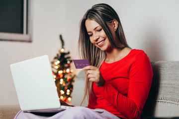 Young woman ordering Christmas gifts online at home