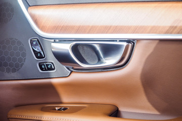Car light brown leather and interior details of door handle with windows power seat controls and adjustments. Luxury car inside. Interior of prestige modern car.
