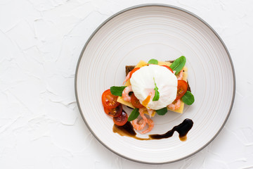 Appetizing sandwich with poached egg, tomato, shrimp and arugula on a plate. Top view