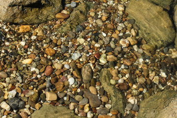 Kieselsteine glitzern im Wasser