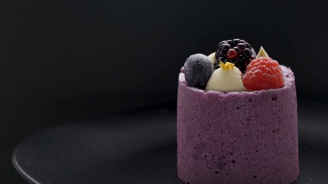 Purple berry mousse cakes with blackberry, blueberry and raspberry on black plate