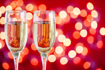 Champagne glasses on light bokeh red background