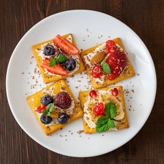 Set of crackers with various fruit close-up on white plate. Top view