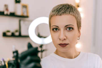 Expressive young tattoo master having workday in salon