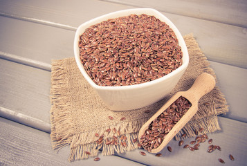 Linseed in a bowl on a wooden background.