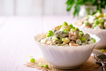 Traditional Russian salad Olivier in bowls on wooden table. Selective focus.