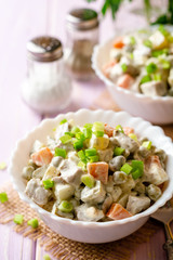 Traditional Russian salad Olivier in bowls on wooden table. Selective focus.
