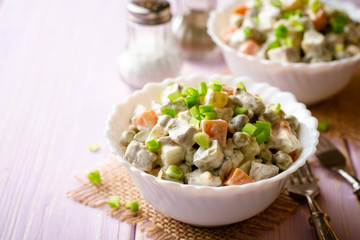Traditional Russian salad Olivier in bowls on wooden table. Selective focus.