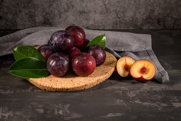 Fototapeta na wymiar Red plums in a cork plate