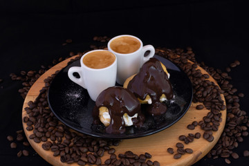 Profiterols and espresso on wood with isolated black background