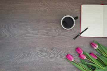 an open notebook with a pen and a bouquet of tulips on a gray background. Free space for text