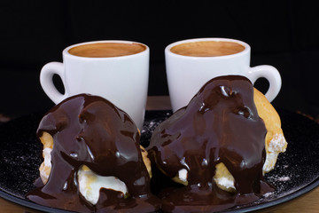 Profiterols and espresso on wood with isolated black background