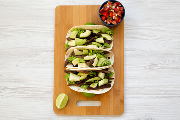 Corn tortillas with grilled beef, avocado, lime and salsa on bamboo board, view from above. Overhead, top view.