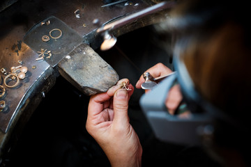 Jeweler saws at a gold ring in authentic jewellery workshop
