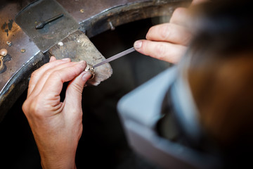 Jeweler working with needle file gold ring  in jewellery workshop