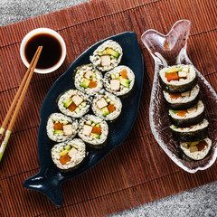 vegan ready-made sushi on the table in fish plates. rolls with fried tofu, cucumber, boiled carrots and fresh avocado. healthy vegan food
