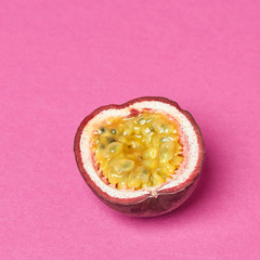 Juicy half passion fruit presented on a pink background with copy space. Tropical fruit. Top view