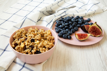 Pink bowl of fruit granola with fruits, side view. Closeup.