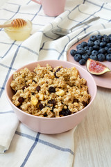 Pink bowl of fruit granola with fruits and honey, side view. Close-up.