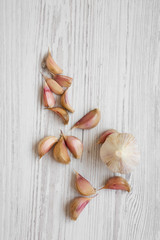 Garlic on white wooden background, overhead view. From above, flat lay. Copy space.