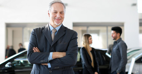Fototapeta premium Happy male car dealer principal inside showroom
