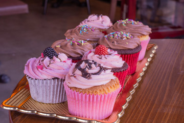 Fresh baked delicious different cupcakes served together with wood background