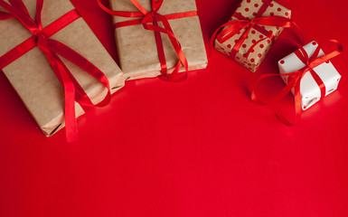 From above view of few wrapped beautiful gifts decorated with colorful ribbons and composed on red.