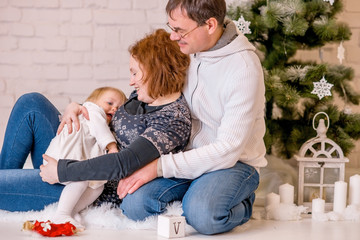 Christmas family photo: mom, dad and baby near the Christmas tree