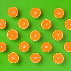 Fruit pattern of fresh orange slices on green background. Flat lay, top view. Pop art design, creative summer concept. Half of citrus in minimal style.