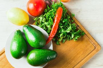 Guacamole - raw organic ingredients, avocado, lemon, pepper, chili in rustic style.