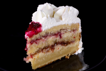 White cream cake with raspberry dressing on it with isolated black background