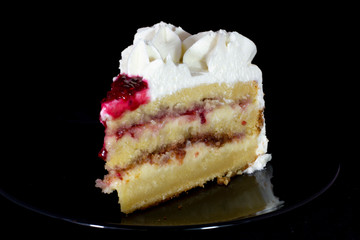 White cream cake with raspberry dressing on it with isolated black background
