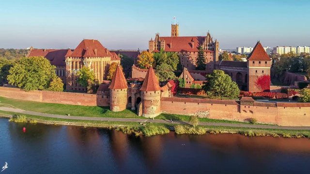 Medieval Malbork (Marienburg) Castle in Poland, main fortress of the Teutonic Knights at the Nogat river. Aerial approaching 4K video in sunset light