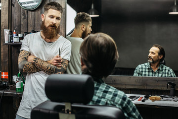 Dark haired man looking at the barber while sitting in armchair