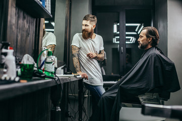 Two thoughtful men looking at the reflection in the mirror