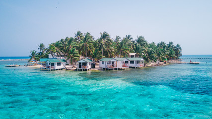 Aerial drone view of Tobacco Caye small Caribbean island with palm trees and bungalows in the...