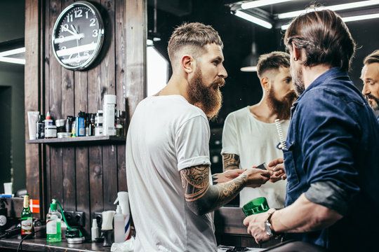 Two curious barbers discussing clipper attachments and looking interested