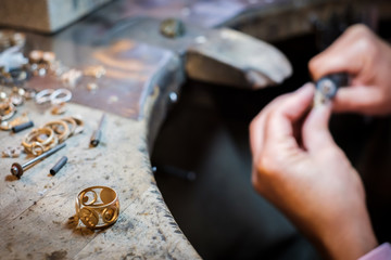 Gold ring on workbench, in the background the jeweler polishing