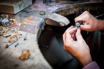 Jeweler polishes gold ring on old workbench in jewelry workshop